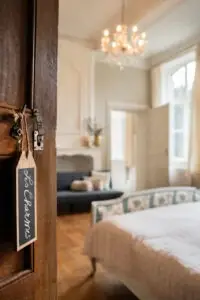 Chambre avec lustre et ardoise « Les Charmes » accrochée à la porte