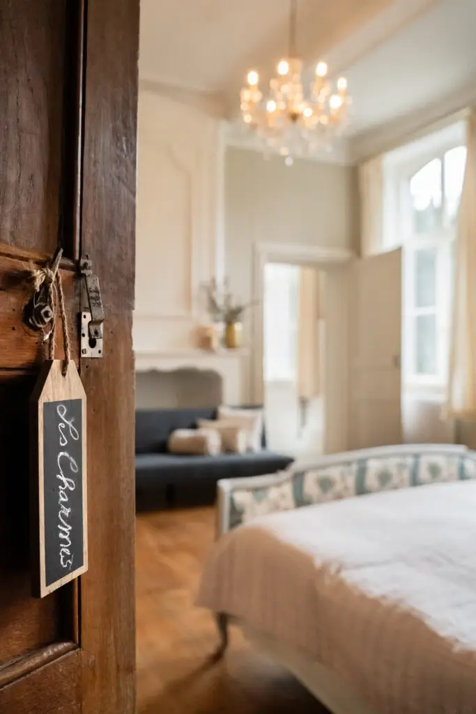 Chambre avec lustre et ardoise « Les Charmes » accrochée à la porte